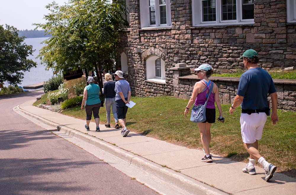 A group of 5 people walks down a sidewalk in Windermere